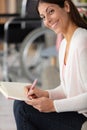 woman writes in book with wheelchair in background Royalty Free Stock Photo