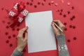 Woman writes goals, checklist, plans and dreams for New Year. Wish list for Christmas. To do list for 2020 year on red Holiday Royalty Free Stock Photo
