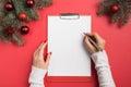 Woman writes goals, checklist, plans and dreams for New Year. Wish list for Christmas. Top view and space for text. Flat lay Royalty Free Stock Photo