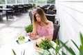 A woman writes a message in phone, in summer in a cafe, a pink dress, rest in a restaurant. Breakfast lunch on summer Royalty Free Stock Photo