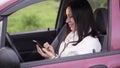 Woman writes a message on a smartphone sitting in the car