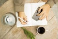 Woman writes in notebook with cell phone and cup of coffee Royalty Free Stock Photo