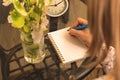 Woman writes on notebook over shoulder view, cozy workspace concept with glass table