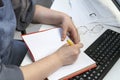 Woman writes in notebook at workplace. Accountant at work. Task manager. Scheduling tasks