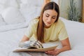 Woman writes in paper notebook with bionic arm lying on bed Royalty Free Stock Photo