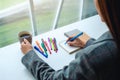 A woman writing on a blank notebook while drinking coffee with colored pens and coffee cup on the table Royalty Free Stock Photo