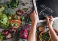 Woman a writing chalk on blackboard, organic food, healthy fresh salad, avocado, greens, arugula