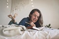 Woman writing her diary whilst lying on bed