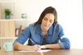 Woman writing a letter on a table at home