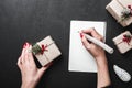 Woman writing letter to Santa Claus at black table. Xmas and Happy New Year card. Flat lay, top view. Royalty Free Stock Photo