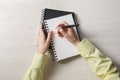 Woman writing in notebook at white wooden table, top view Royalty Free Stock Photo