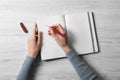 Woman writing in notebook at white wooden table, top view Royalty Free Stock Photo