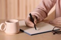Woman writing in notebook at wooden table indoors, closeup Royalty Free Stock Photo