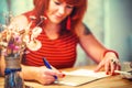 Woman is writing in notepad in coofee bar.