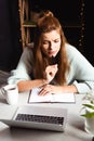 Woman writing in notepad while watching webinar on laptop in cafe Royalty Free Stock Photo