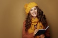 Woman writing personal goals in notebook on beige background