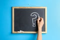 Woman writing question mark with chalk on blackboard