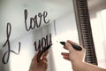 Woman writing romantic message I Love You on mirror in room, closeup