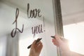 Woman writing romantic message I Love You on mirror in room, closeup
