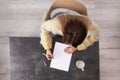Woman writing on sheet of paper at table indoors Royalty Free Stock Photo