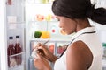 Woman Writing On Spiral Book Near Refrigerator Royalty Free Stock Photo