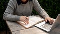 A woman writing or taking notes in her notebook while working remotely at a table outdoors Royalty Free Stock Photo