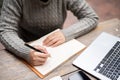 A woman writing or taking notes in her notebook while working remotely at a table outdoors Royalty Free Stock Photo
