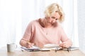 Woman Writing at Wooden Desk while Reading From Book Royalty Free Stock Photo