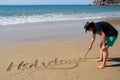 Woman writing the words Holidays in the sand