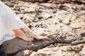 Woman& x27;s bare feet with elegant pedicure and bracelets on the rocks, close-up. Woman sitting on the rocky beach