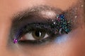 Woman's eye with makeup and colorful crystals. Close up