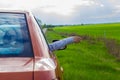 A woman& x27;s hand in a car window against the background of a green meadow and a stormy sky with sun rays. Beautiful Royalty Free Stock Photo