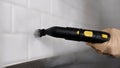 Woman cleaning the kitchen with a steam cleaner, hands close-up. A woman& x27;s hand cleans the tiles with a vacuum Royalty Free Stock Photo
