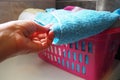 A woman's hand is feeling a cotton colored towel from a basket with dirty laundry. Laundry sorting and washing