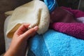 A woman's hand is feeling a cotton colored towel from a basket with dirty laundry. Laundry sorting and washing
