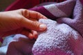 A woman's hand is feeling a cotton colored towel from a basket with dirty laundry. Laundry sorting and washing