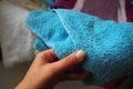 A woman's hand is feeling a cotton colored towel from a basket with dirty laundry. Laundry sorting and washing