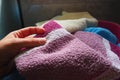 A woman's hand is feeling a cotton colored towel from a basket with dirty laundry. Laundry sorting and washing