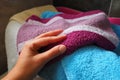 A woman& x27;s hand is feeling a cotton colored towel from a basket with dirty laundry. Laundry sorting and washing