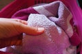 A woman's hand is feeling a cotton colored towel from a basket with dirty laundry. Laundry sorting and washing