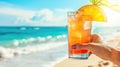 Woman& x27;s Hand holding cold iced tea or tropical cocktail on beach exotic vacation, against backdrop of bright sea Royalty Free Stock Photo