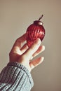 Woman& x27;s hand holding red Christmas tree decoration, minimalistic color scheme, lots of texture. Royalty Free Stock Photo