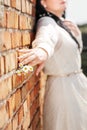 Woman& x27;s hand holding small blossoming chamomile flower bouquet on brick wall background at sunmmer sunny day