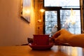 A woman& x27;s hand holds a cup of coffee at a table in a cafe near the window in winter, drinking coffee Royalty Free Stock Photo