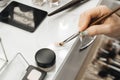 A woman's hand holds makeup brushes and dials a cosmetic product onto the brush. close-up Royalty Free Stock Photo