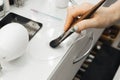 A woman's hand holds makeup brushes and dials a cosmetic product onto the brush. close-up Royalty Free Stock Photo