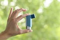 A woman& x27;s hand holds a spray inhaler for asthma attacks on the street.