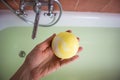 Woman& x27;s hand putting yellow bath bomb in a bathtub full of water top view. Spa Royalty Free Stock Photo