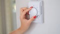 Woman& x27;s hand regulating the temperature of central heating of house on thermostat Royalty Free Stock Photo