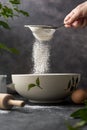 Woman& x27;s hand sifting flour through sieve. Selective focus. Baking, cooking, pastry abstract concept. Dark background